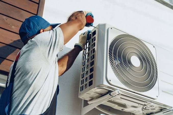 Technicien NOVACLIM installant l'unité extérieure d'un climatiseur en hauteur